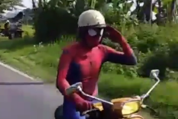 Pemotor berkostum Spiderman menunggangi Vespa PTS kuning